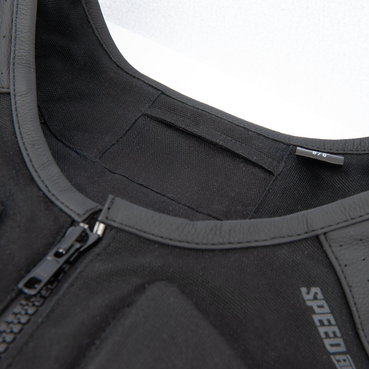 Close-up of True Grit vest front zipper and 'Speed' branding on a white background